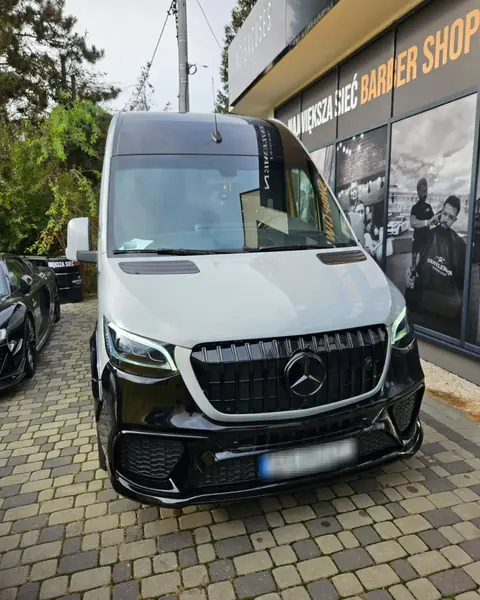 Jasny Mercedes Sprinter VIP z czarnym przodem, zaparkowany na kostce brukowej – widok z przodu